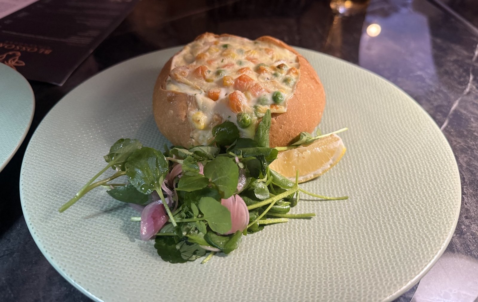 くり抜いたパンに注がれたクリームスープと、添えられた葉野菜のサラダ