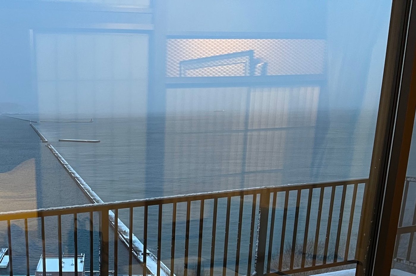 銀鱗荘の部屋の窓から見た小樽の港。防波堤と海、雪の積もった屋根