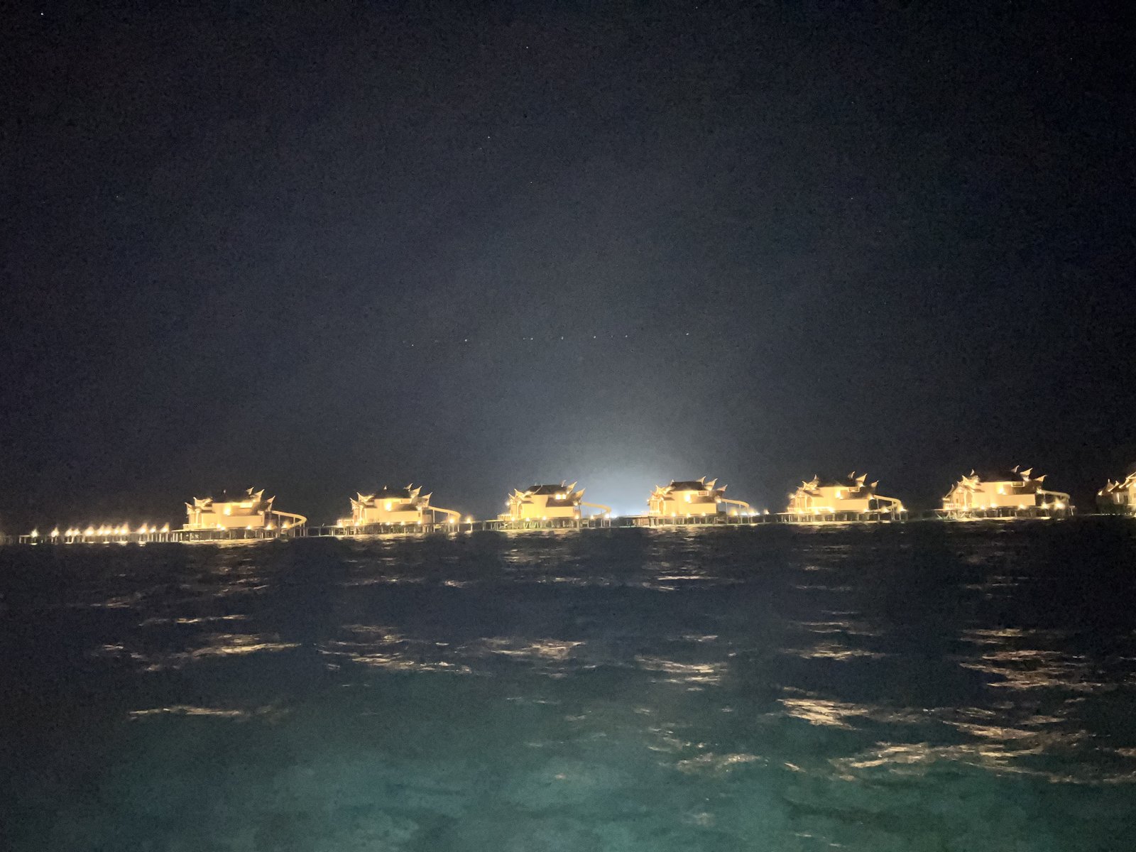 海の向こうに見える夜の水上ヴィラの灯り