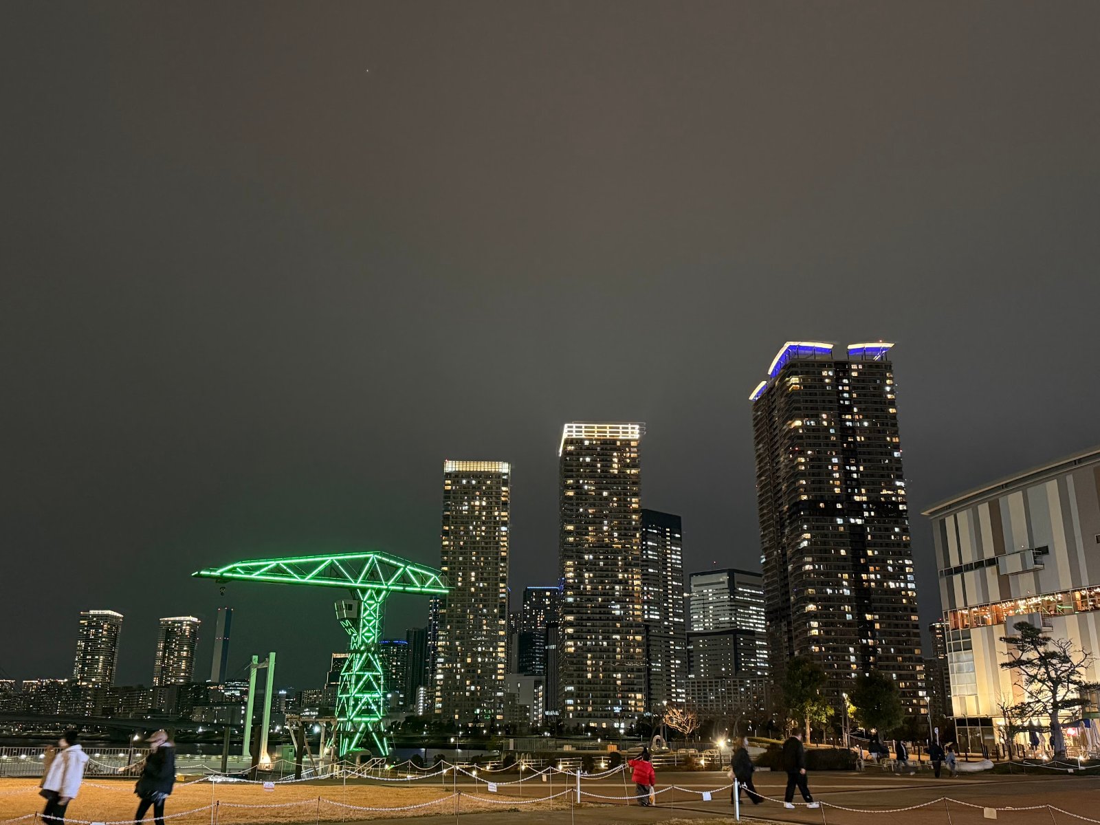 夜の豊洲。ライトアップされたクレーンと、高層マンションの明かり